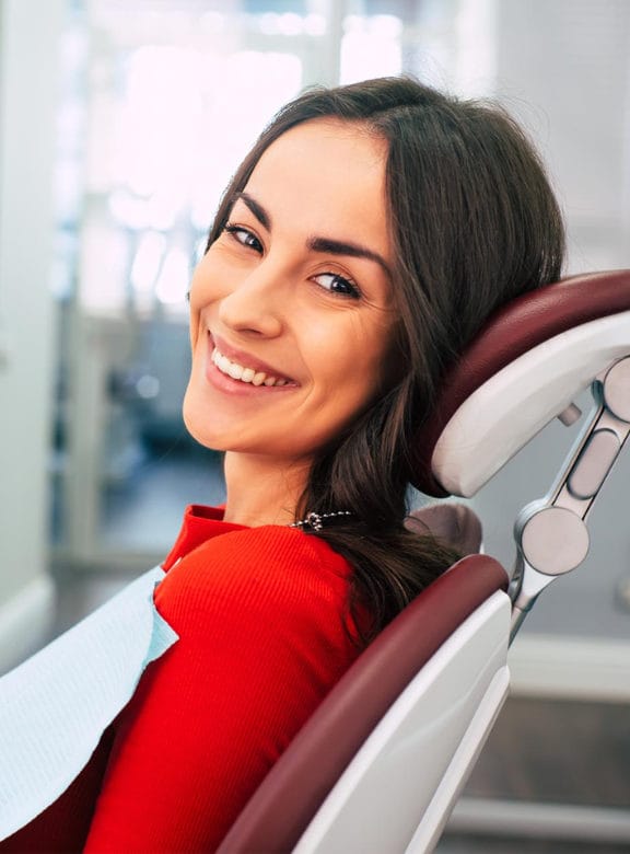 woman sitting in a dental chair smiling at the camera